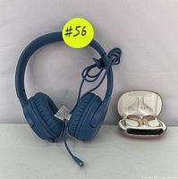Blue wired over-ear headphones with cushioned ear cups and cable, alongside white wireless earbuds in an open charging case with silver accent.
