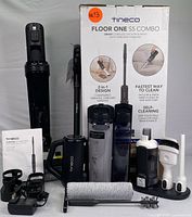 Main box, upright vacuum unit, dual water tanks, handheld vac, wand, bottles and dock arranged in front of backdrop