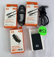Photo showing the iQ wall charger box, two boxes for USB-C to Lightning cables, and unboxed charging cables and charger.