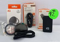 Full view of the boxed wireless charger, coiled braided USB-C cable, and boxed USB-C wall charger with green lot sticker.