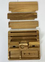 Top-down image of the docking station with four wooden panels laid out, showing slots and compartments for devices and accessories.