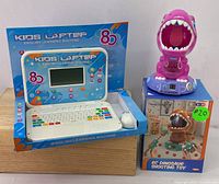 Kids laptop still in packaging alongside electronic dinosaur toy boxed and out of box
