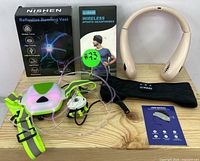 NISHEN Reflective Running Vest with LED light on green base, Ic-dolice wireless headphones with packaging and wearable neck fan, plus related accessories and cables