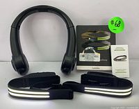 Black rechargeable neck fan worn around neck and LED headlamp boxed with headlamp and battery packet alongside reflective adjustable straps.