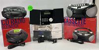 Wide shot showing entire set of audio equipment including two CD radio boombox boxes with the equipment on top, Bluetooth CD micro system in center with remote, and AM/FM cassette radio on right.