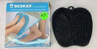 Beskar foot scrubber mat from front showing soft silicone bristles next to product box with usage image and green price sticker.
