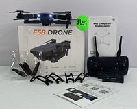 Full lot layout including drone, remote control, spare propellers, propeller guards, instruction manual, and E58 drone box.