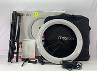 Complete Mobifoto ring light kit including tripod, ring light, power adapter, carrying case, and manual placed in front of original box.