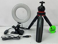 Photo of the USB-powered LED ring light with clip-on mount next to the Mobifoto branded adjustable tripod with three legs.