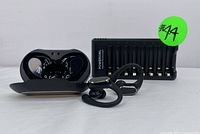 Photo of the wireless earbuds in their open charging case placed in front of the multi-slot battery charger with batteries loaded.