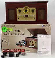 Wooden Proscan 6-in-1 Turntable on top of its box with instruction manual and power cords visible.