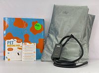 Photo showing gray pet heating pad folded with attached black temperature control device and chew-resistant power cord. Box for the pet heating pad also visible.