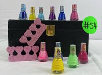 Photo showing all 10 colorful nail polishes, 2 pink glittery toe separators, and closed black storage case with gold clasp.