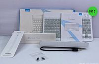 Wireless keyboard, its retail box, user manual, stylus pen box, USB charging cable and replacement tips shown in photo.