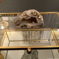 Close-up of quartz geode mineral on glass display box showing crystal interior and brass knob on box