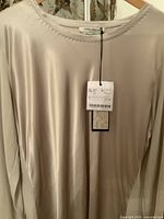 Front view of the Marina Rinaldi silk top showing smooth fabric and neckline, original tag attached.
