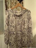 Lightweight, flowey long sleeve blouse with patterned print on hanger.