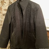 Front view of vintage black quilted MARINA RINALDI jacket showing zip closure, pockets, and stitch detailing.