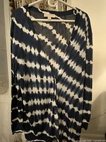 Cardigan hanging on a hanger to show full length and pattern.