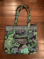 Full view of the Vera Bradley quilted tote bag showing its colorful floral and paisley pattern, long handles, and zippered front pocket.