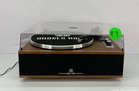 Front view with clear dust cover closed, showing wood veneer plinth and front speaker grille with Angels Horn logo