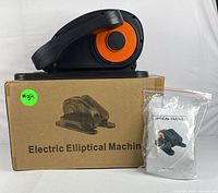 Electric elliptical machine on top of its box with user manual in plastic bag.