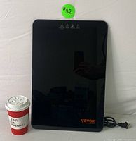 Black flat rectangular heating plate with glossy surface showing VEVOR logo and power cord.