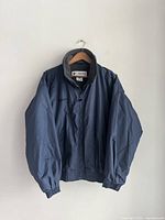 Front view of men's blue Columbia jacket showing elastic cuffs and waistband, zippered front and fleece-lined collar.