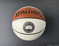 Top view of basketball showing Spalding logo on orange half and Canada Goose Arctic Program logo on white half.