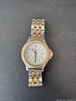 Front view of the vintage women's Swiss Military watch showing the white dial with Arabic numerals, red second hand, and two-tone metal band.