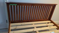 Full view of the wooden bed frame showing slatted headboard and wooden slats base supporting mattress.