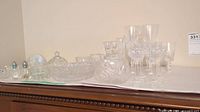 Overview of entire collection of crystal glassware on flat surface, showing flutes, bowls, candle holders, and other pieces.