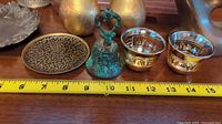Four decorative metal items displayed with measuring tape showing size approximately 4 inches for the plate