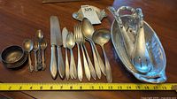 Full view of cutlery and pewter items arranged with measuring tape showing size