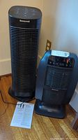 Honeywell black air purifier and space heater positioned on a floor near a wall outlet, both showing front and top control panels.