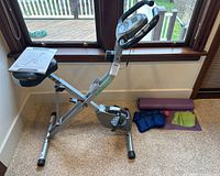 Exercise bike with folded design, black padded seat, and attached manual.