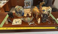 Overview of all international themed home decor items arranged on a wooden surface including various animal figurines and cultural carvings.
