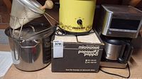 Microwave popcorn popper box, yellow Crock-Pot, large stainless steel saucepan with lid and strainer on top, displayed together