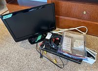 Photo of Toshiba 21-inch TV with combination VHS/DVD player, assorted cables, and owner's manual on carpeted floor