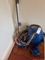 Full view of Kenmore blue canister vacuum with hose, wand, power cord, and two blue accessory pieces on the floor.