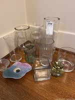 Full view of all vases on wooden surface against wall, varying heights and shapes