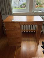 Full view of the wooden desk showing the three drawers side by side and open leg space on the right.