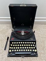 Open case showing typewriter inside with cleaning brush beside it