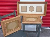 Three vintage solid wood picture frames displayed: one large rectangular frame with three cutouts, two smaller oval cutout frames placed on a chair and table.