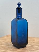 Photo showing the side of the cobalt blue glass bottle embossed with "AYERS" text.