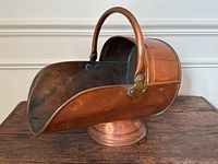 Side view showing copper body, curved front lip, handle attachment and dents