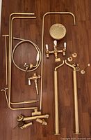 Top-down overview of all gold-plated brass components laid out on wooden floor
