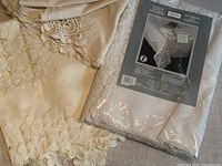 Sealed Eaton Battenburg lace tablecloth in original packaging next to unfolded linens