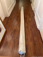 Plastic-wrapped fabric blind laid out on hardwood floor
