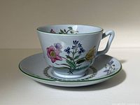 Cup and saucer set showing floral pattern, light gray background, and green edging